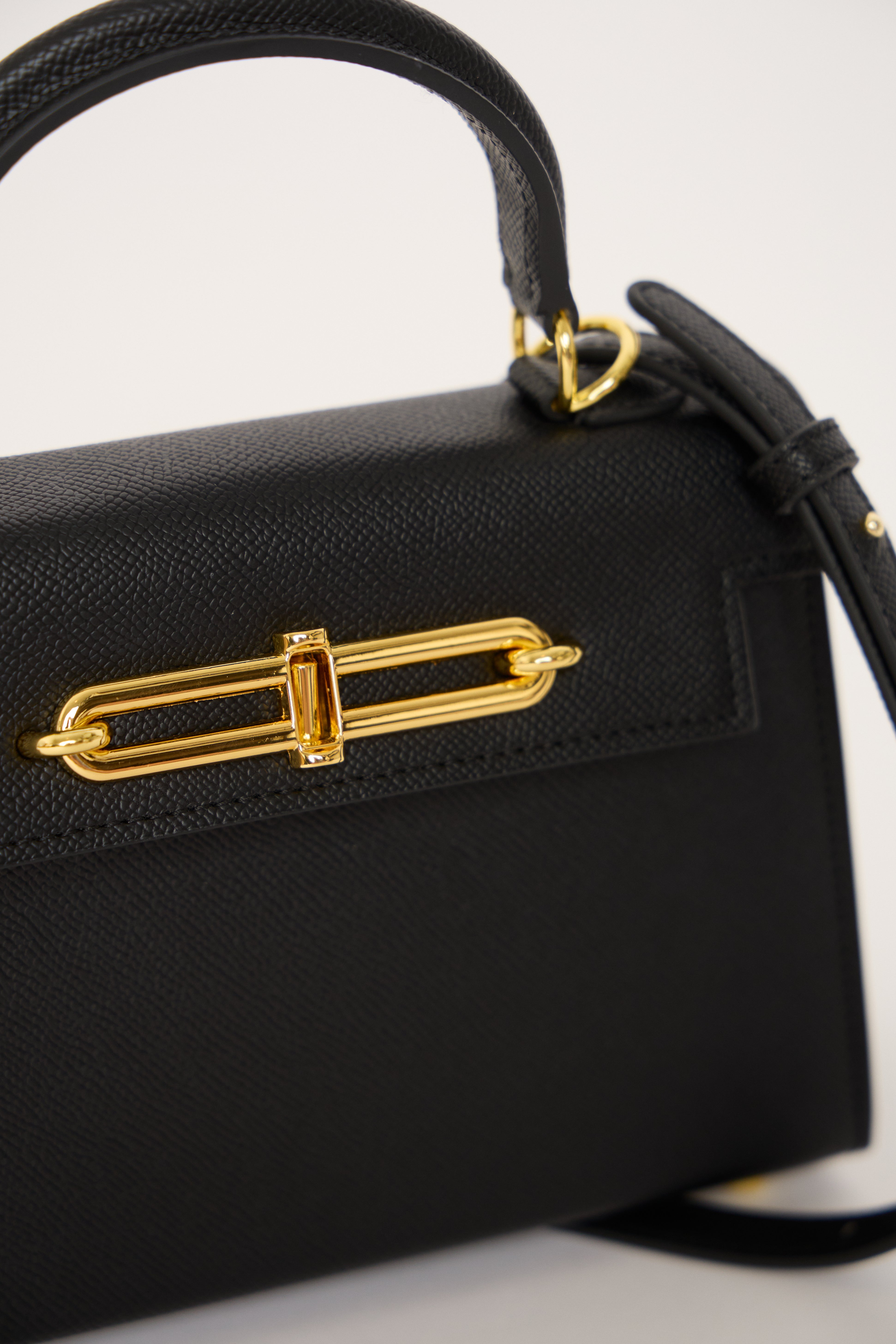 Black handbag with gold accents on a white background