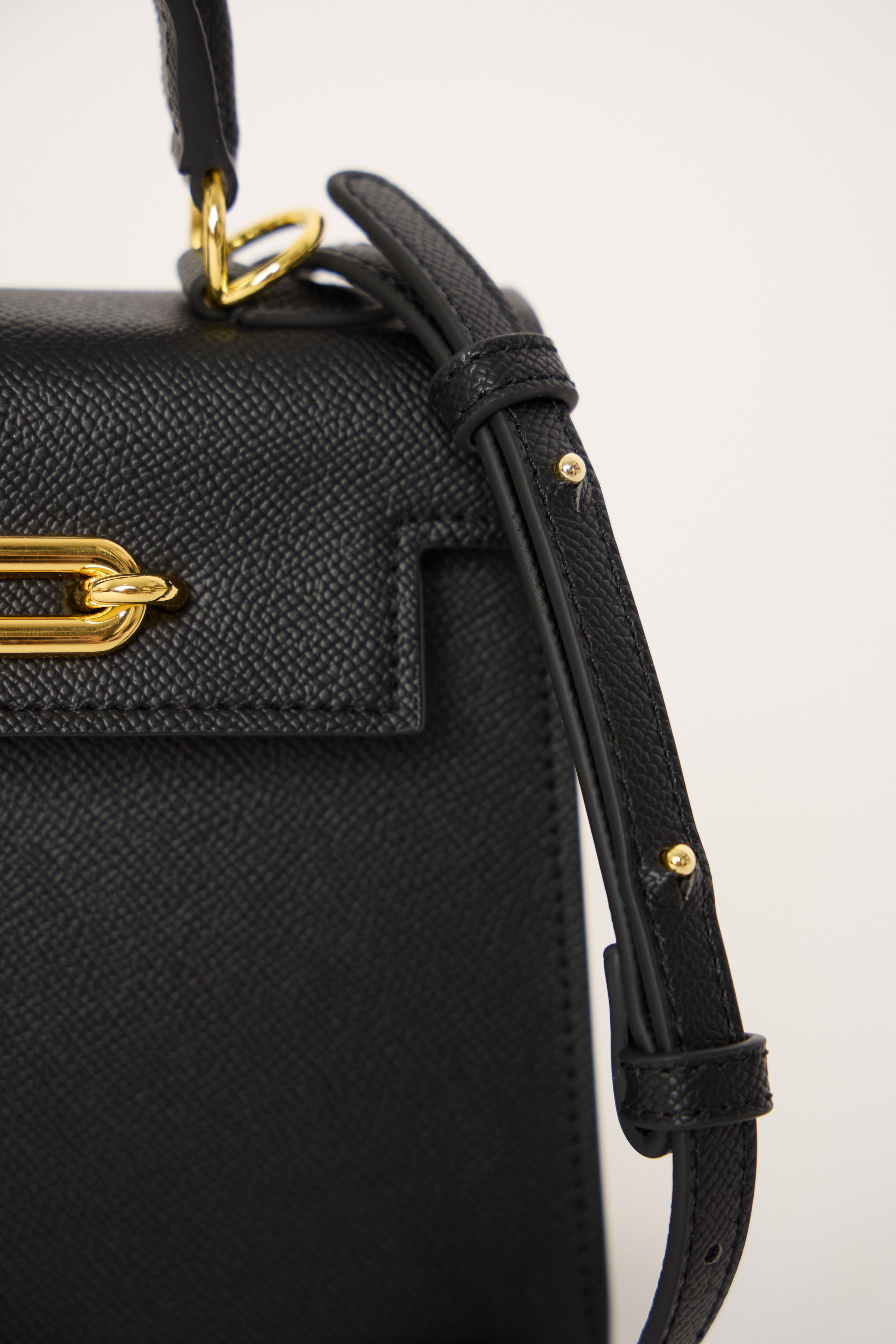 Black handbag with gold accents on a white background